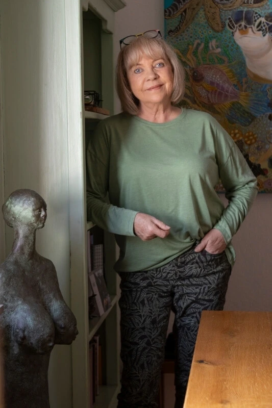 Ella della Rovere steht an ein Bücherregal angelehnt